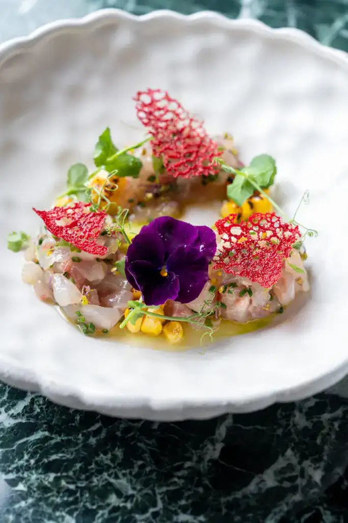 Feinschmecker-Teller mit frischer Meeresfrüchte, essbaren Blumen und kunstvoller Garnitur, kunstvoll zubereitet und präsentiert in modernem Gourmet-Design.