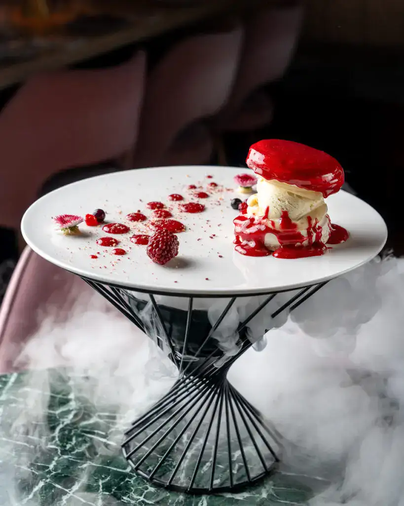 Kreatives Desserts, modernes Porzellan, elegante Präsentation, köstliches Eis mit Beeren, innovative Menügestaltung.